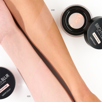 Puder Catrice Bright & Blur Soft Pink na jasnym i opalonym ramieniu, obok dwóch otwartych opakowań sypkiego pudru.