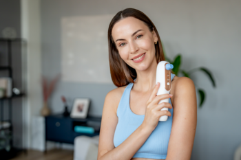 Uśmiechnięta kobieta z białym Beautifly Hydraclear PRO, urządzeniem do wodorowego oczyszczania twarzy.