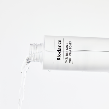 Biała butelka Biodance Skin Refining Mild PHA Toner (łagodny tonik złuszczający) z wylewającym się płynem na białym tle.