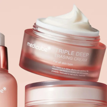 Otwarty słoik kremu Medicube Triple Deep Erasing Cream, różowy, z białą, puszystą konsystencją, na pastelowym tle.
