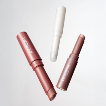 Trzy błyszczące cienie w sticku Glitter Eye Pen, w odcieniach brązu i bieli, uniesione, z iskrzącym wykończeniem.