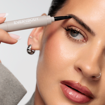 Kobieta aplikuje na brew Everybody Brow Pomade z Pędzelkiem Ash Brown. Produkt 2w1 w jasnoszarej tubce.
