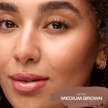 Zbliżenie na opaloną twarz kobiety z brązowymi włosami, efekt użycia Lumene Bronzer w sztyfcie Medium Brown.