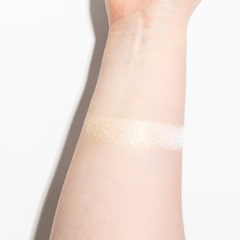 Sypki pigment Shine Your Day! 102 Vanilla, ciepły waniliowy shimmer na jasnym przedramieniu.