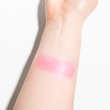 Widok z bliska: Sypki pigment Shine Your Day! 114 Cerise, intensywny perłowy różowy swatch na przedramieniu.