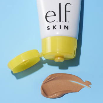 e.l.f. Skin Suntouchable Whoa Glow SPF 30, biała tubka z otwartą żółtą zakrętką, krem o promiennej konsystencji na niebieskim tle.