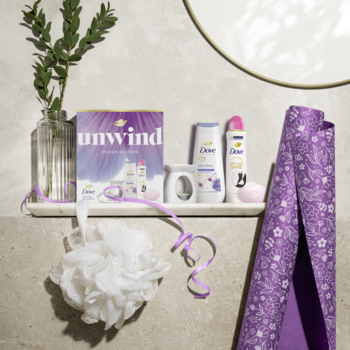Zestaw Dove Unwind Relaxing Selection: żel, antyperspirant, mydło i kominek na marmurowej półce, fioletowe dodatki.