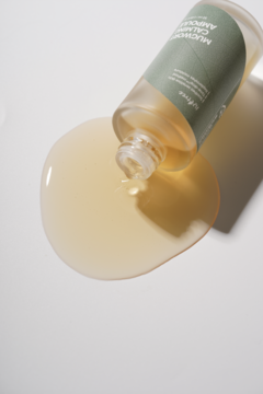 Kojąca ampułka Isntree Mugwort Calming z piołunem wylewa się z butelki, tworząc kałużę na białym tle, widok z góry.