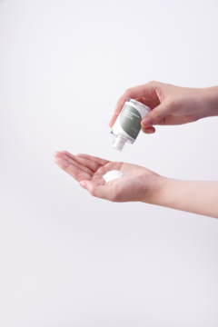 Ręce wylewają z butelki Isntree Mugwort Calming Powder Wash - biały proszek do mycia twarzy na otwartą dłoń.