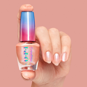 Ręka trzyma szybkoschnący lakier OPI RapiDry Stun N Done w odcieniu nude, z gradientową nakrętką. Paznokcie z połyskiem.