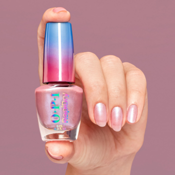 Różowy perłowy lakier szybkoschnący OPI RapiDry Flash N Flirty, butelka z gradientową zakrętką w dłoni.