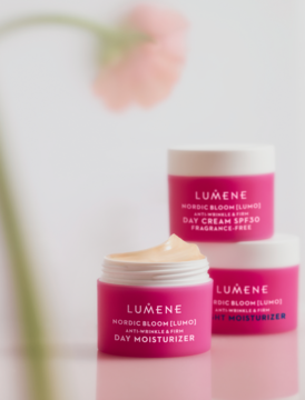 Trzy różowe słoiki Lumene Nordic Bloom [Lumo] kremu na dzień, jeden otwarty z widocznym beżowym kremem, pod kątem.
