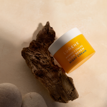 Pomarańczowy słoiczek Lumene Nordic-C Glow Renew Night Cream z witaminą C, widok pod kątem na drewnie.