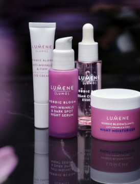 Zestaw Lumene Nordic Bloom: fioletowe serum, biały krem pod oczy, olejek i krem na noc, na ciemnym, odbijającym tle.