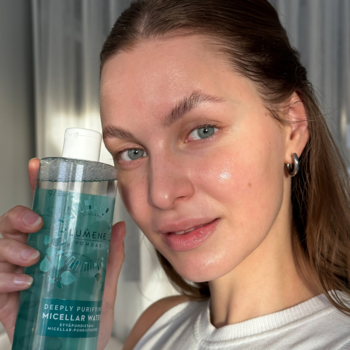 Kobieta trzyma butelkę Lumene Puhdas Deeply Purifying Micellar Water dla cery mieszanej, zielono-niebieski płyn.