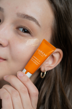 Kobieta nakłada Lumene Nordic-C rozświetlające serum pod oczy z witaminą C, widoczny produkt na skórze.
