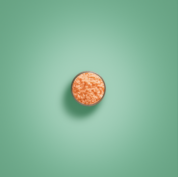 Collistar Talasso Anti-Eta peeling do ciała, pomarańczowy z solą morską, w okrągłym naczyniu na miętowym tle.