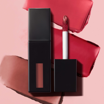 e.l.f. Glossy Błyszcząca szminka w płynie Polished Peach. Czarne opakowanie, aplikator z produktem, smugi na różowym tle.