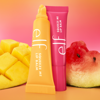 Dwa balsamy e.l.f. Squeeze Me Lip Balm (mango, arbuz) w tubkach z owocami na tle różowo-pomarańczowym.
