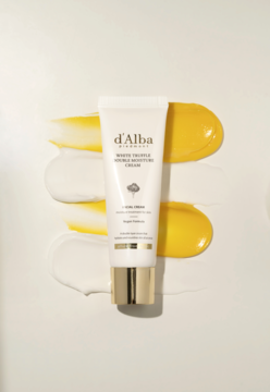 Krem d'Alba White Truffle Double Moisture Cream w białej tubce, ze złotymi akcentami, otoczony smugami serum i kremu.