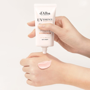 Ręka wyciskająca różowy d’Alba White Truffle Waterfull Tone-Up Sunscreen SPF 50+ na drugą dłoń. Zbliżenie.