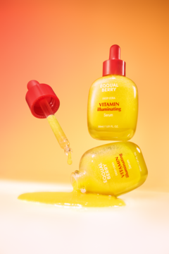 Serum rozświetlające Eqqualberry Vitamin Illuminating, dwie żółte butelki z kroplomierzami, jedna rozlana na gradientowym tle.
