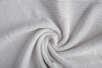 Biały, miękki ręcznik 650gsm złożony w spiralę, z widoczną puszystą teksturą i subtelnymi wzorami.