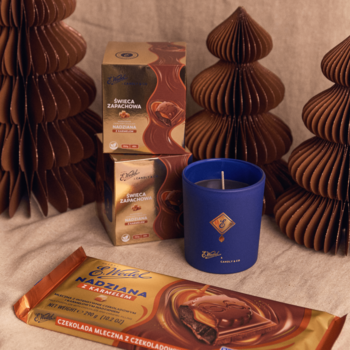 Niebieska świeca E. Wedel Nadziana z karmelem, czekolady i brązowe karbowane drzewka na jasnym tle.