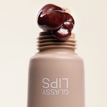 Zbliżenie na Say Hi Glassy Lips peptydowy balsam w odcieniu Berry, lśniąca, gęsta konsystencja wydobywająca się z tubki.