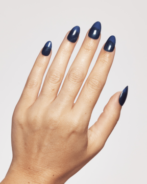 Ardell Nail Addict Gel Strips. Lewa dłoń z długimi, błyszczącymi, granatowymi paznokciami żelowymi w szpic.