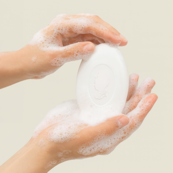 Pani Walewska RELAX & GLOW: białe, owalne mydło w kostce z wytłoczonym logo, trzymane w spienionych dłoniach.