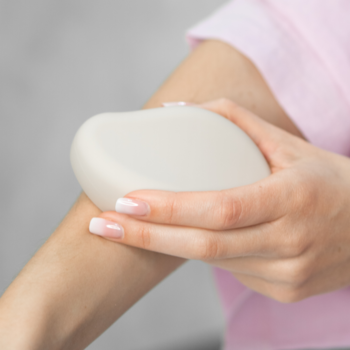Dłoń z french manicure delikatnie przesuwa kremowy depilator Nano Glass po przedramieniu, wygładzając skórę.