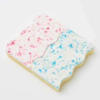 Płaskie ciasteczko z białym lukrem posypanym różowymi i niebieskimi drobinkami, podzielone falistą linią.