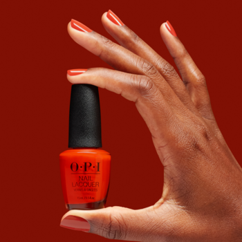 OPI, lakier do paznokci w butelce 15ml, żywy pomarańczowo-czerwony odcień, trzymany przez dłoń z pomalowanymi paznokciami.