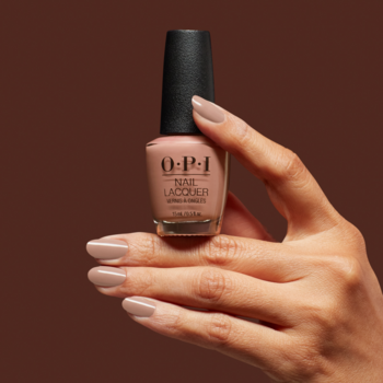 OPI klasyczny lakier do paznokci w kolorze nude, butelka trzymana przez dłoń z dopasowanym manicure.