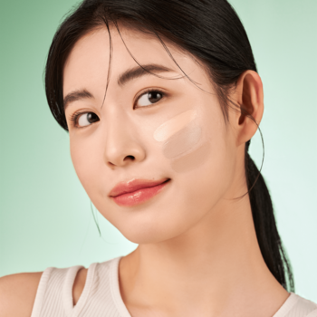 Zbliżenie na kobietę z dwoma testowymi paskami półmatowego kremu BB na policzku na zielonym tle.