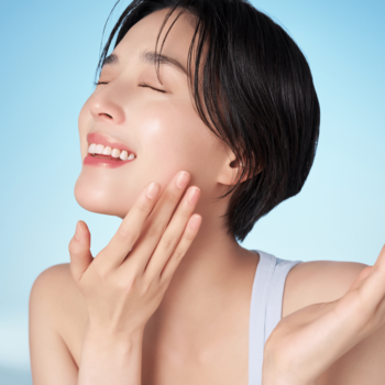 Promienna kobieta dotyka nawilżonej cery, ciesząc się efektem głęboko nawilżającego serum do twarzy.