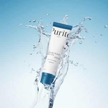 Biało-niebieska tubka Purito B5 Panthenol Re-barrier Cream, unosząca się w powietrzu, otoczona rozbryzgami wody.