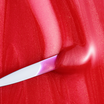 Zbliżenie balsamu Fluff Candy Lip Balm Cherry Crush, gęsta, perłowa, wiśniowa masa rozsmarowywana szpatułką.