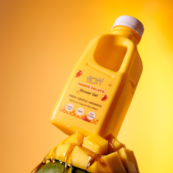 Żółty żel pod prysznic Fluff Mango Gelato na kawałkach mango, widok pod kątem, tropikalne tło.