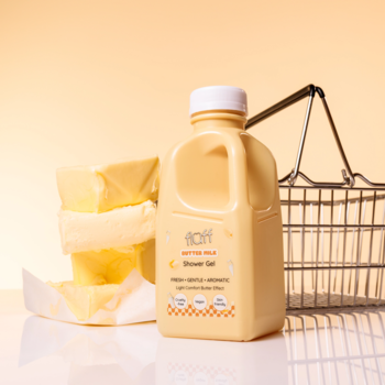 Fluff Butter Milk Żel pod prysznic, żółta butelka jak karton mleka, obok kostki masła i koszyk.