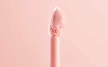 Zbliżenie na różowy aplikator balsamu do ust z jasnoróżową, błyszczącą formułą pianki marshmallow.