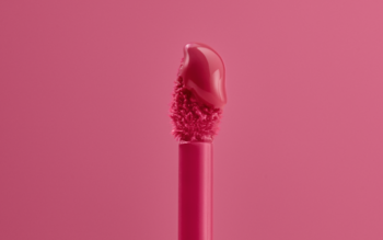 Zbliżenie na różowy aplikator nawilżającego balsamu do ust z błyszczącą, żelową formułą.