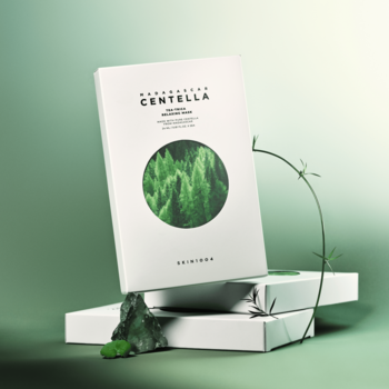 Maska SKIN1004 Centella Tea-Trica Relaxing, białe opakowanie z zielonym wzorem, na stosie pudełek, z kamieniami i pnączem.