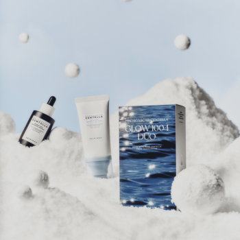 Zestaw Skin1004 Glow Duo: ciemna ampułka i krem SPF w tubce. Biały, zimowy krajobraz z niebieskim pudełkiem.