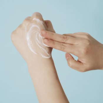 SKIN1004 Hyalu-Cica Gentle Cleansing Milk. Dłoń rozprowadza białe, kremowe mleczko na skórze.