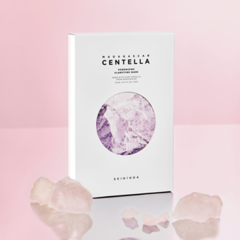 Biała maska SKIN1004 Centella Poremizing w pudełku z fioletowym wzorem, obok różowe kryształy na pastelowym tle.