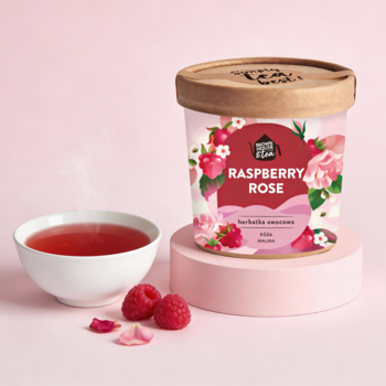 Okrągłe opakowanie herbatki owocowej Raspberry Rose, obok parujący napar i świeże maliny na różowym tle.