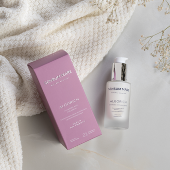 Sensum Mare Algorich serum przeciwzmarszczkowe, butelka z pompką i różowe pudełko, na dzianinie i jasnym tle, z góry.