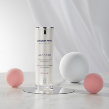Sensum Mare Algopro serum 5% ceramidów w białej butelce na lustrzanej podstawce, obok różowa i biała kula.